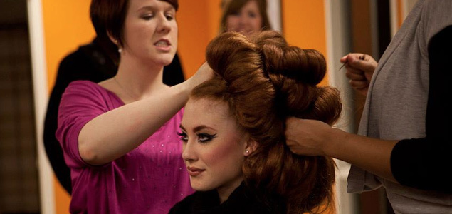 Stylists in the High School Student Program prepare a model for the runway.